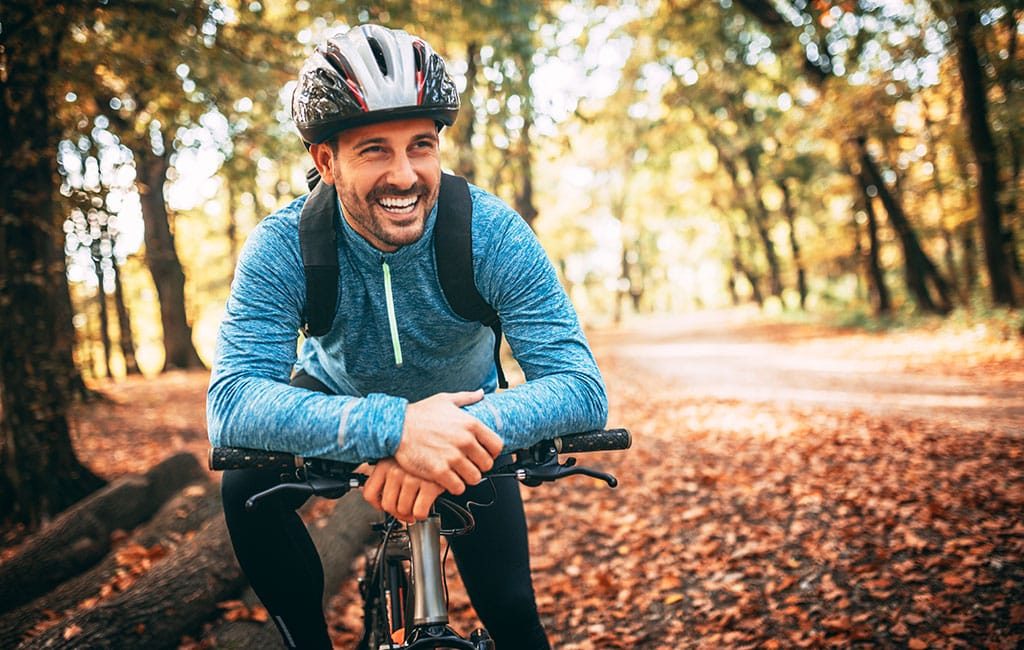 Man rides bike outside with beautiful smile from emergency dental services at Evergreen Dental in Palmer Alaska.